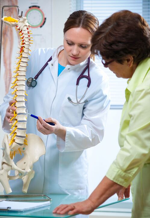 il medico mostra l'osteocondrosi della colonna vertebrale su un modello